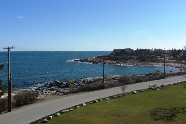 A coastal road with a clear view of the sea and rocky shoreline.
