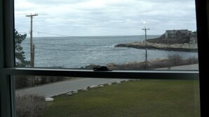 A coastal view from a window, including a road, grassy area, and a distant house by the water. - The Seafarer Inn (Rockport)