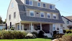 A two-story house with a front porch, a chimney, and a well-maintained lawn. - The Seafarer Inn (Rockport)