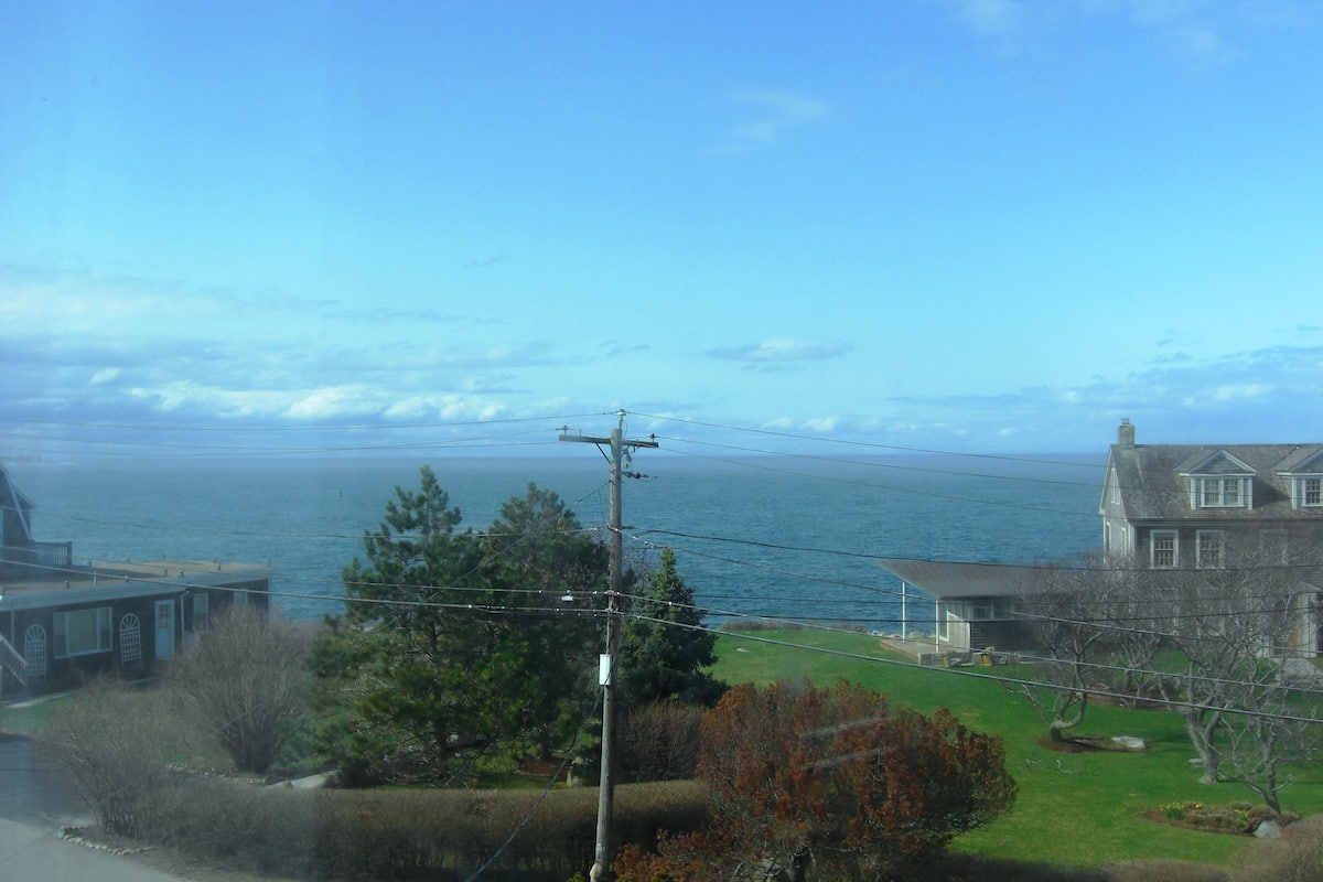 A coastal view with a house, a road, and a body of water.
