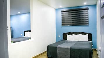 A bedroom with a bed, a window with blinds, and a mirror.