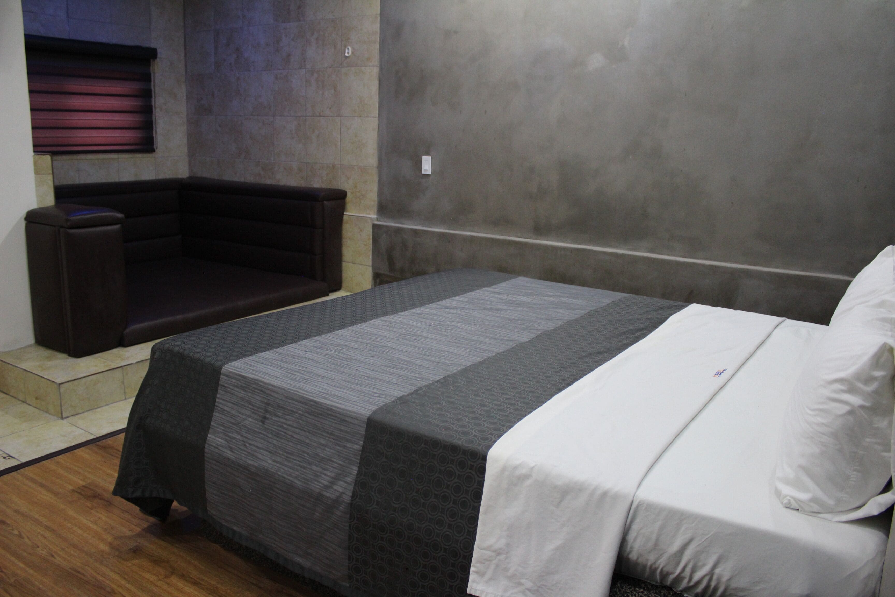 Habitación de hotel con cama, sofá y una pequeña zona de estar.