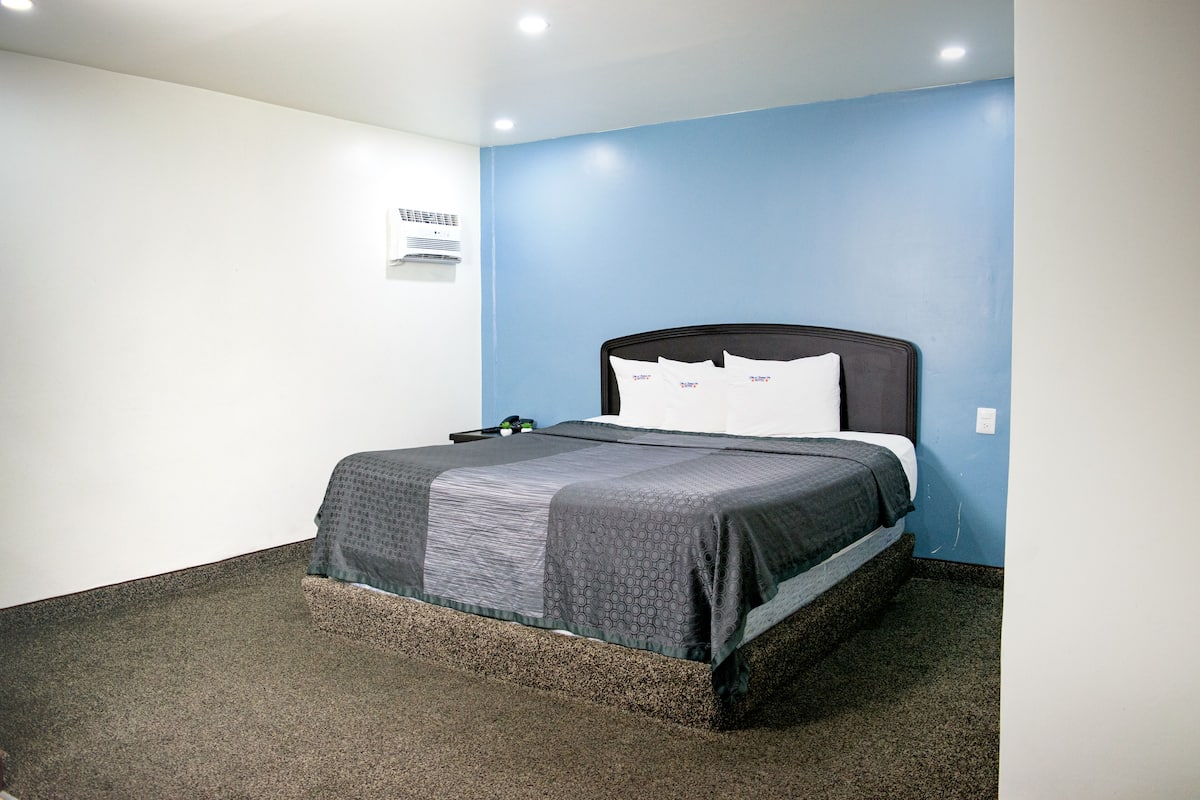 Ein Hotelzimmer mit einem Bett, einer Wand-Klimaanlage und Teppichboden.