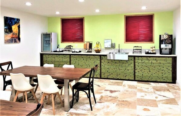 Un restaurante con una mesa y sillas de madera, una barra con una máquina de café y una cortina roja.