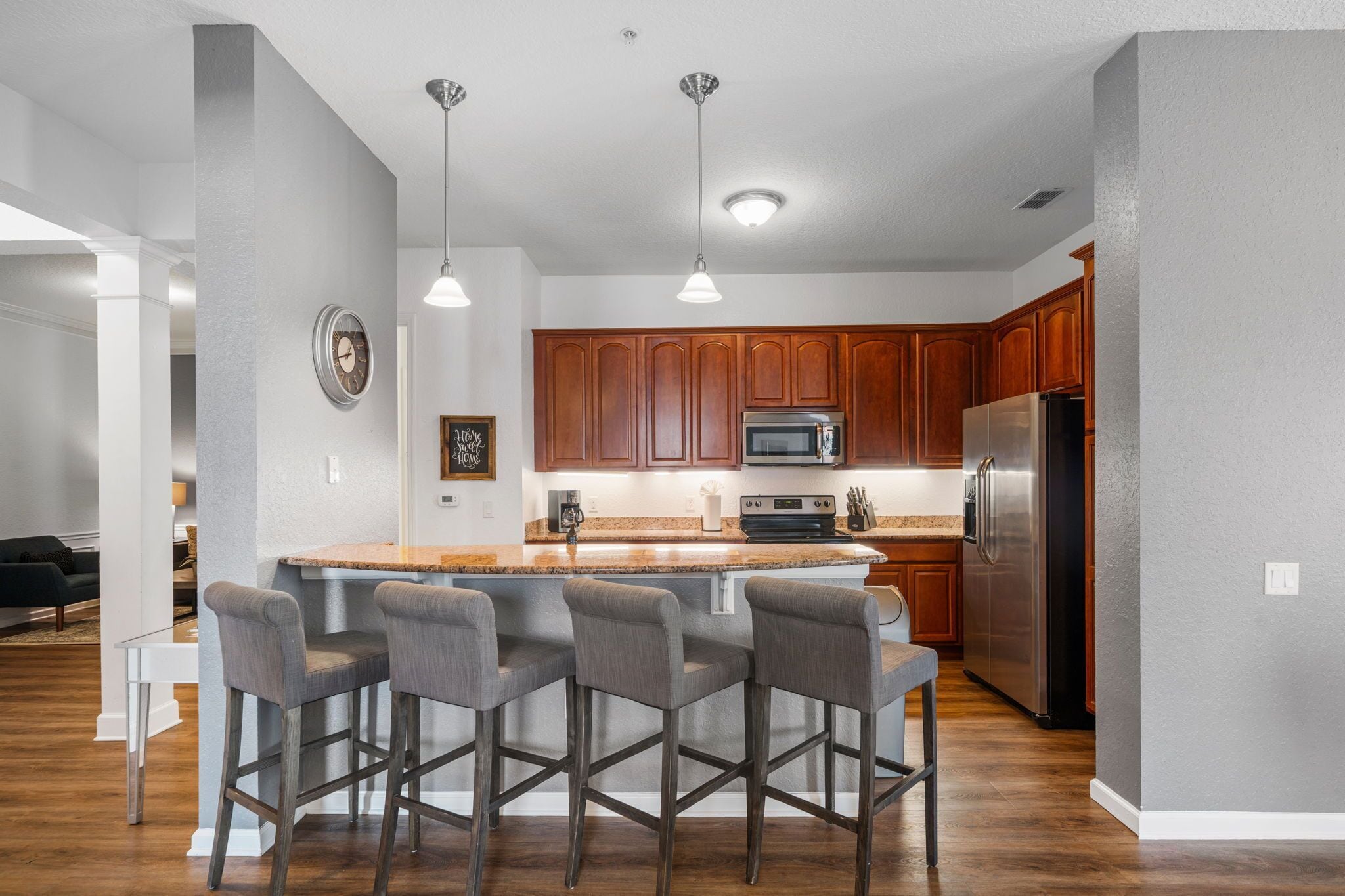 A modern kitchen with wooden cabinets, stainless steel appliances, and a central island with bar stools.