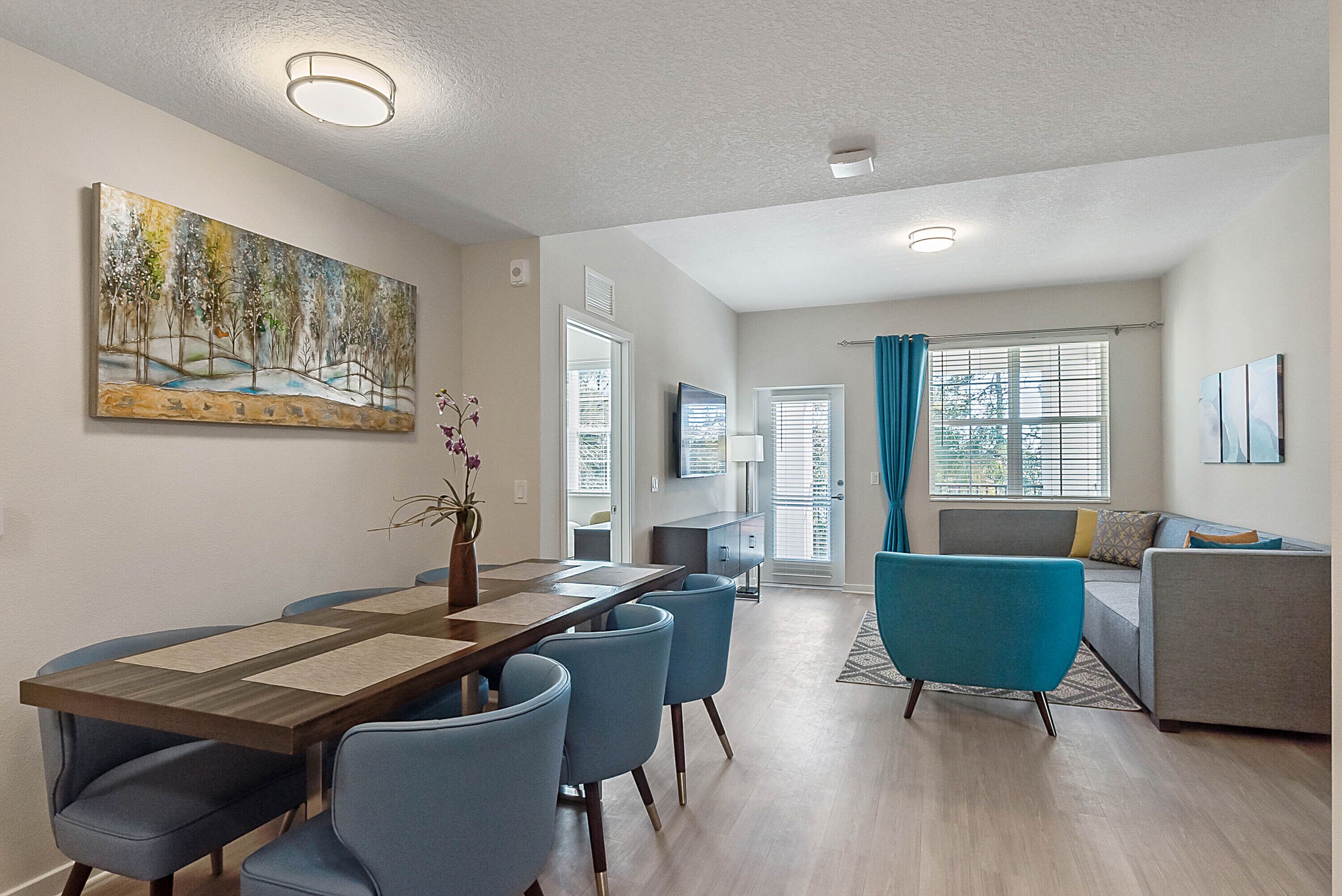 A modern living room with a dining area, a sofa, and a TV.