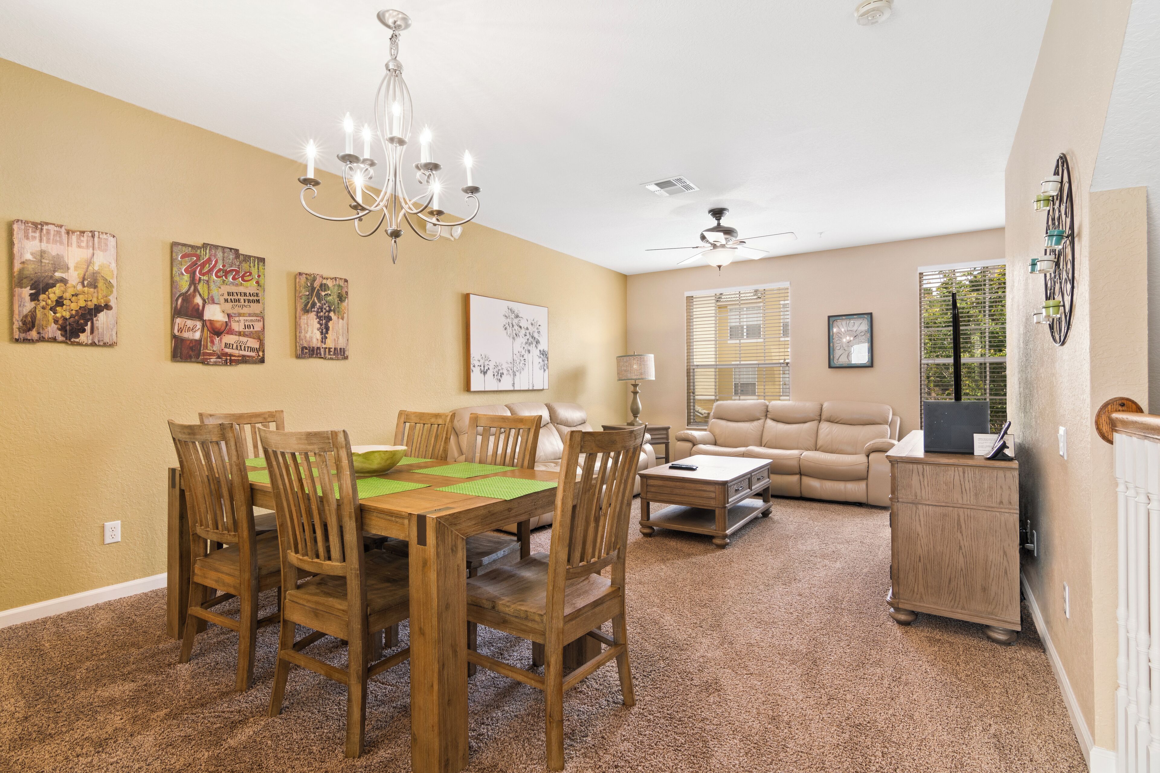 A dining area with a wooden table and chairs, a chandelier, and wall art.