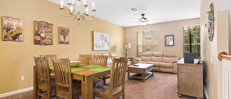A dining area with a wooden table and chairs, a chandelier, and wall art.