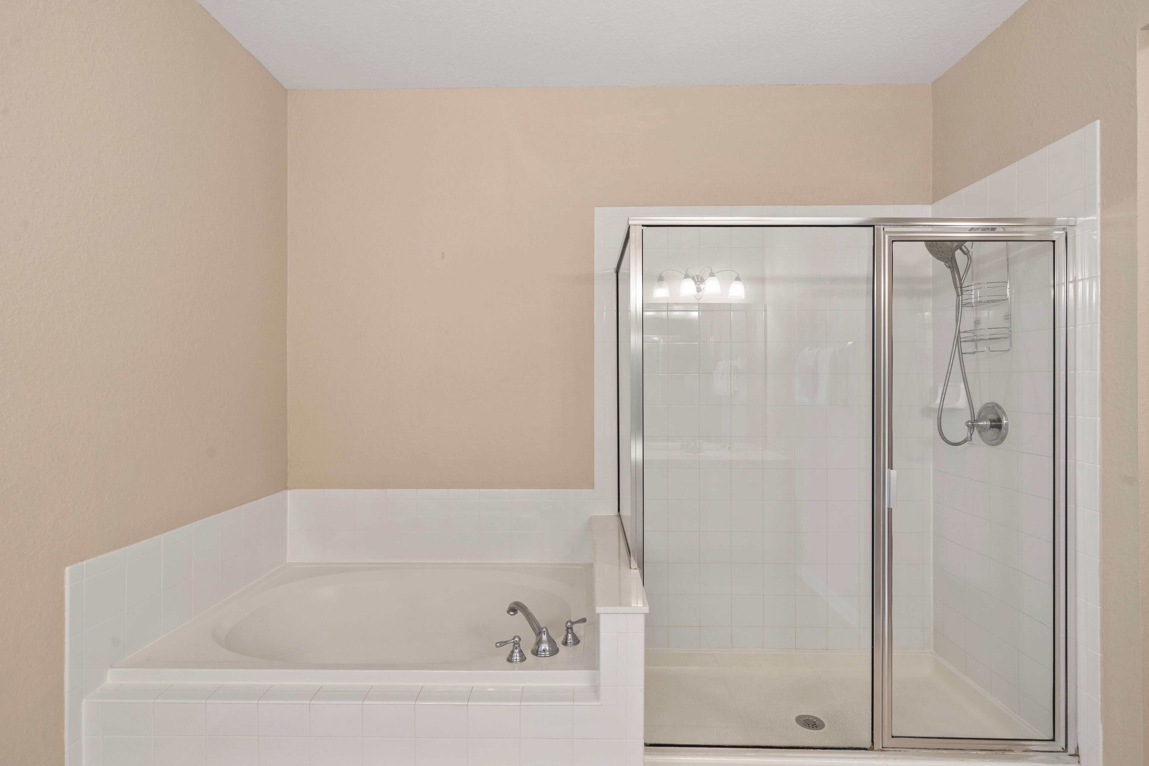 A bathroom with a bathtub and a glass-enclosed shower stall.