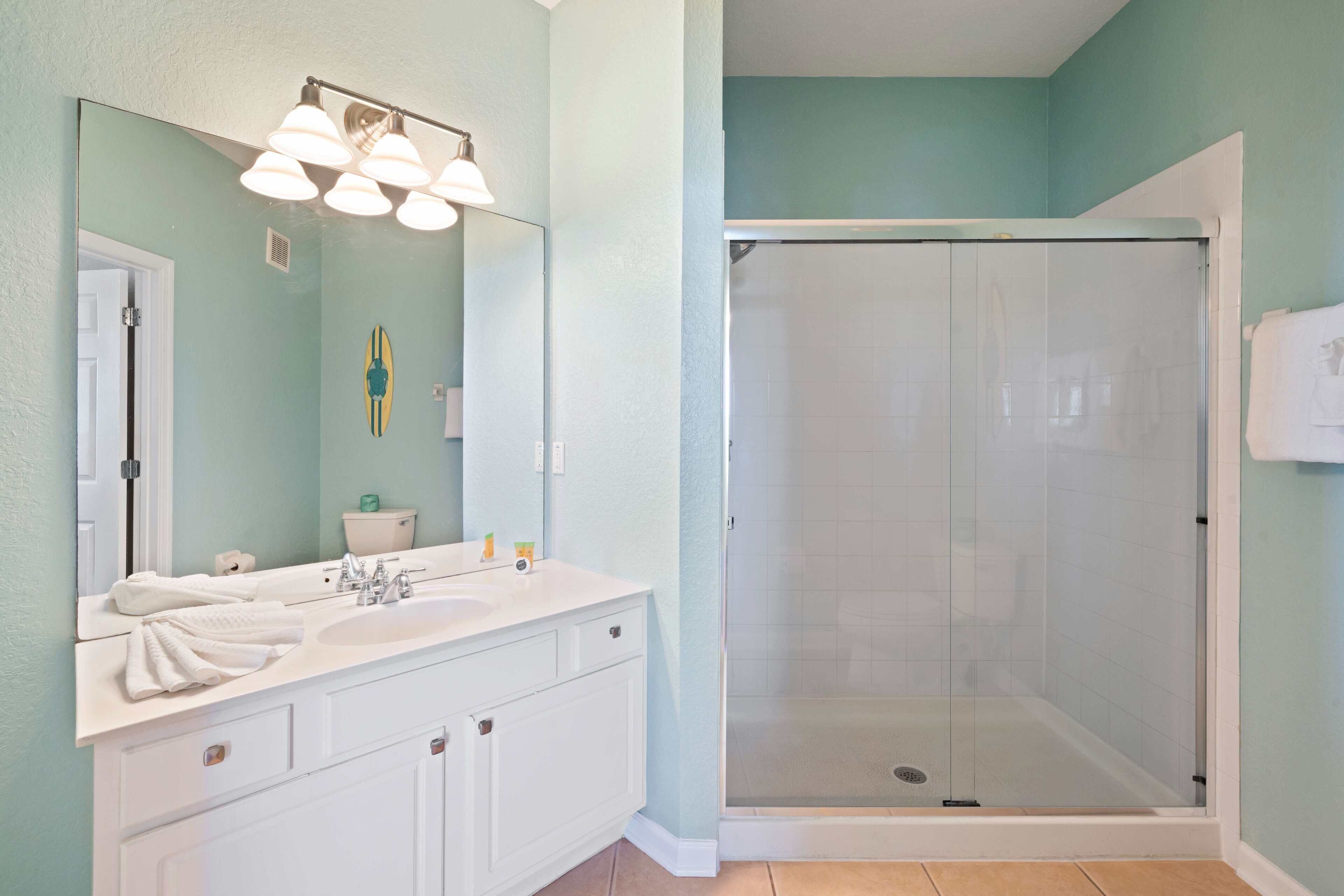 A bathroom with a white vanity, a large mirror, and a glass-enclosed shower.
