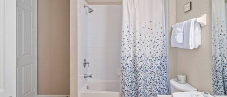 Un baño con bañera, inodoro y cortina de ducha.