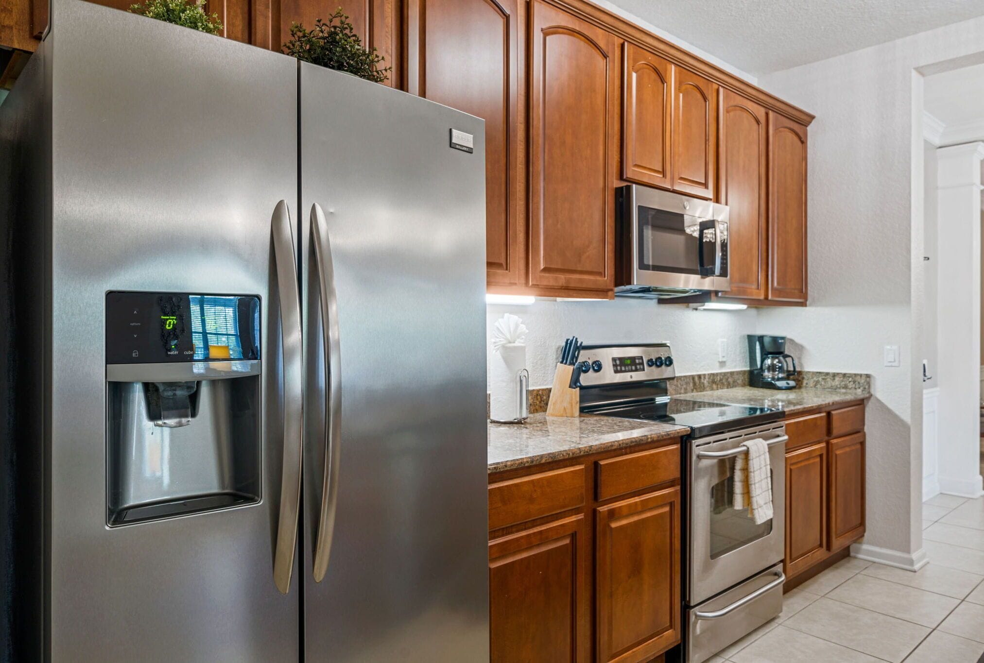 A kitchen with stainless steel appliances, wooden cabinets, granite countertops, and a built-in microwave.