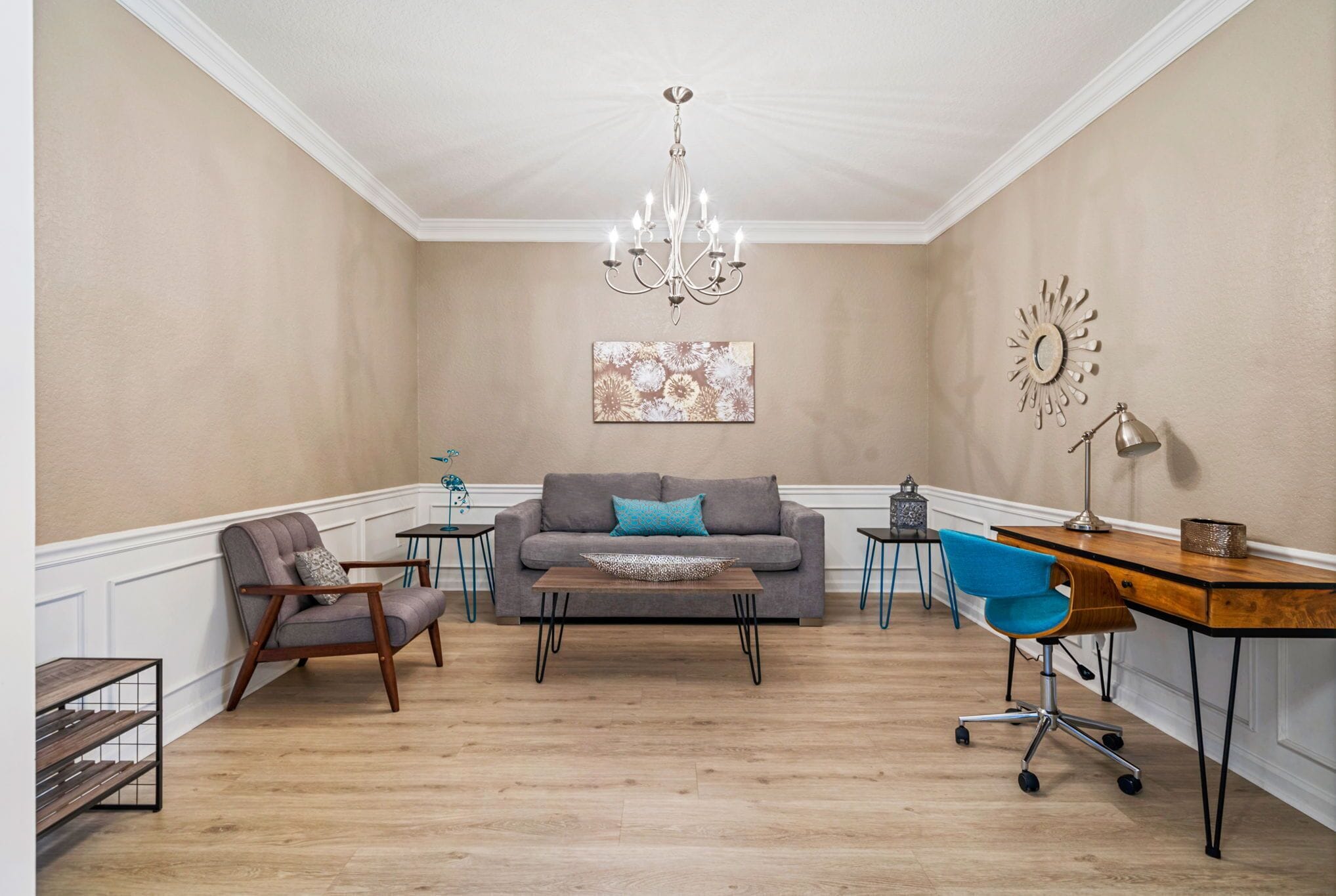 A living room with a sofa, armchair, coffee table, and a desk with a chair.