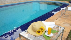 A poolside area with a glass table holding a hat, a towel, and a glass of orange juice. - Beulah Hotel Boutique (Asunción)