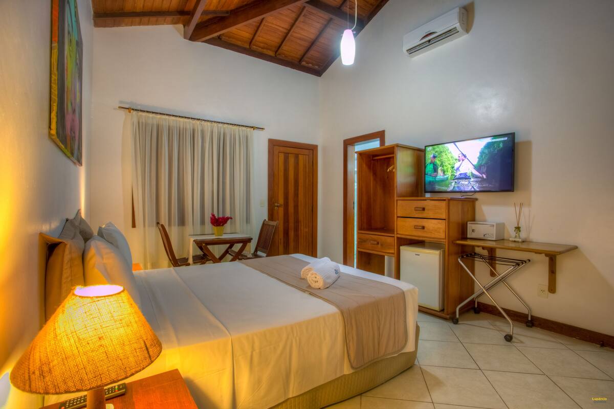 A hotel room with a bed, a desk, a television, and a small kitchenette.