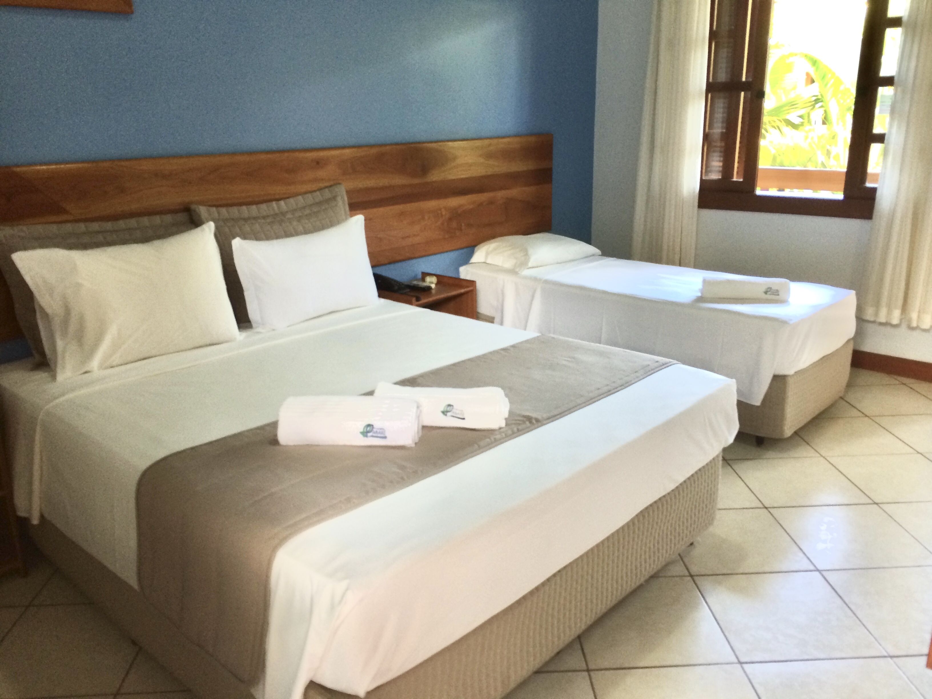 A hotel room with a large bed, a smaller bed, and a nightstand.