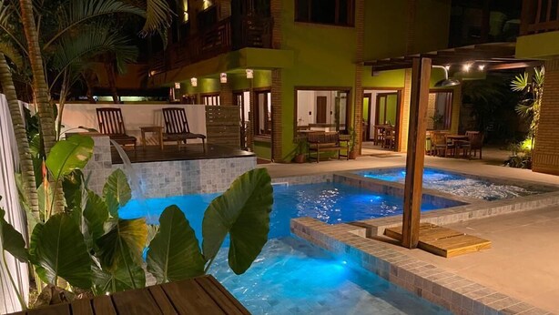 A pool area with a wooden deck, a hot tub, and a covered seating area. - Pousada Abaré (Itacaré)