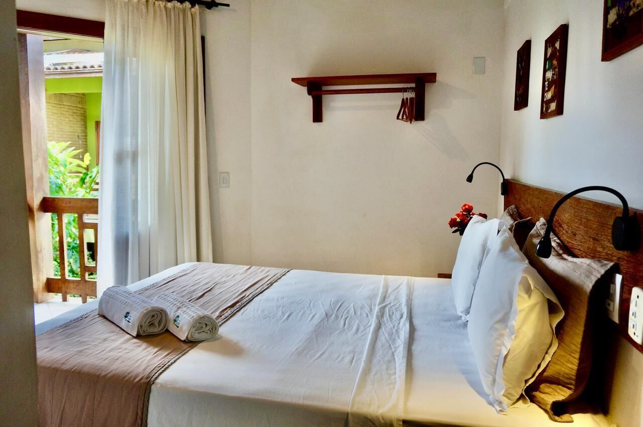 A neatly made bed with a white bedspread and pillows, a wooden headboard, and a small shelf above it.
