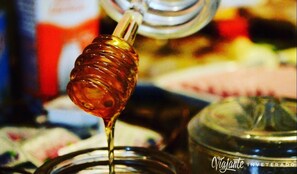 A close-up of a honey dipper dripping honey into a jar. - Pousada Abaré (Itacaré)