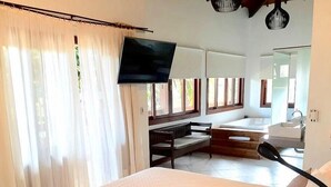 A hotel room with a bed, a TV, a bench, a bathtub, and a sink. - Pousada Abaré (Itacaré)
