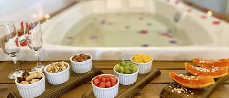 A spa setting with a hot tub, various snacks, and decorative flowers.
