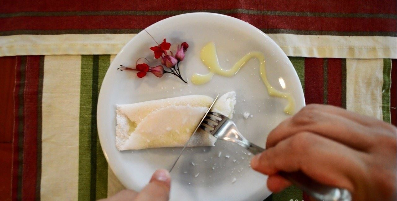 Eine Person verwendet eine Reibe auf einem Teller mit Käse und Blumen.
