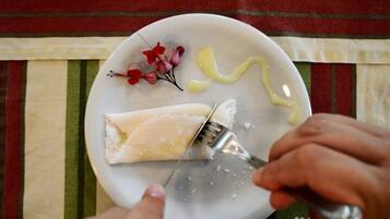 Eine Person verwendet eine Reibe auf einem Teller mit Käse und Blumen.