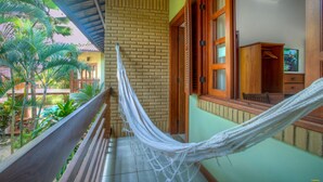 A hammock on a balcony with a view of a brick wall and a wooden door. - Pousada Abaré (Itacaré)