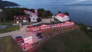 Ein Motel mit roter und weißer Fassade, einem Parkplatz und Blick auf das Wasser.