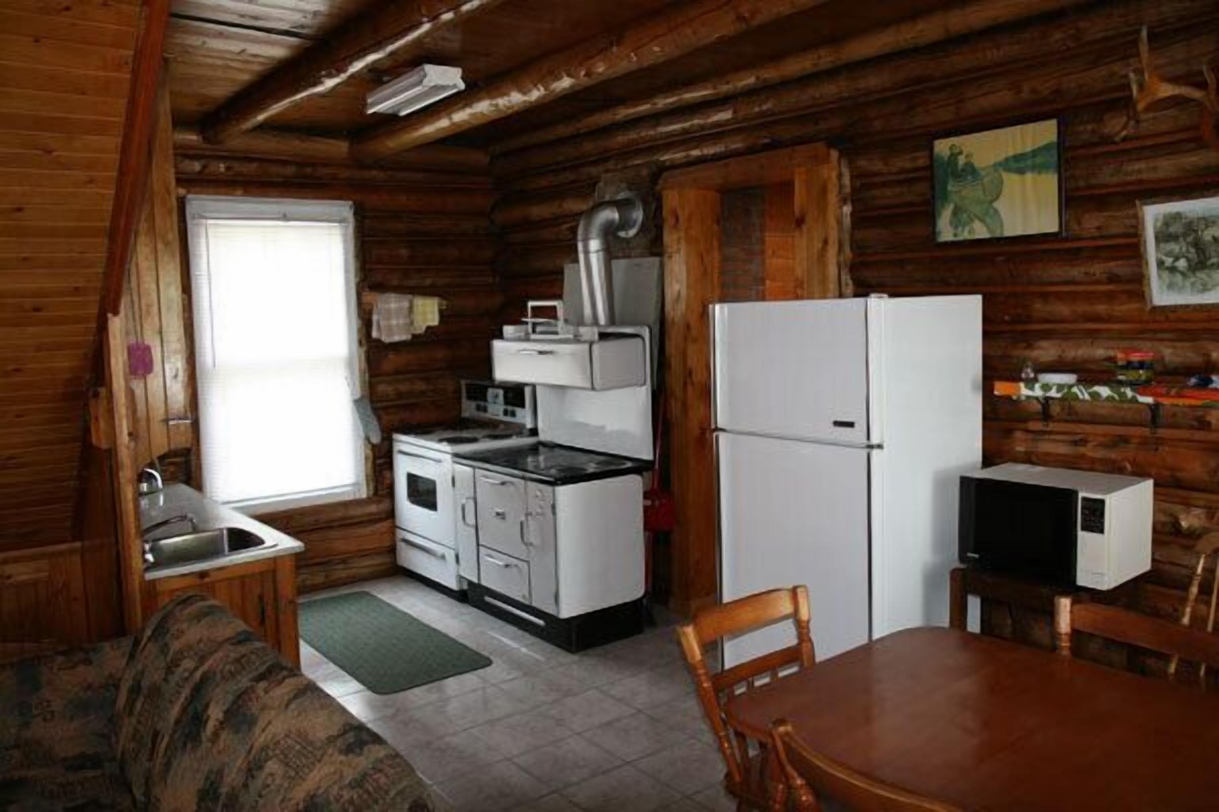 A compact kitchen with a sink, stove, refrigerator, and microwave.