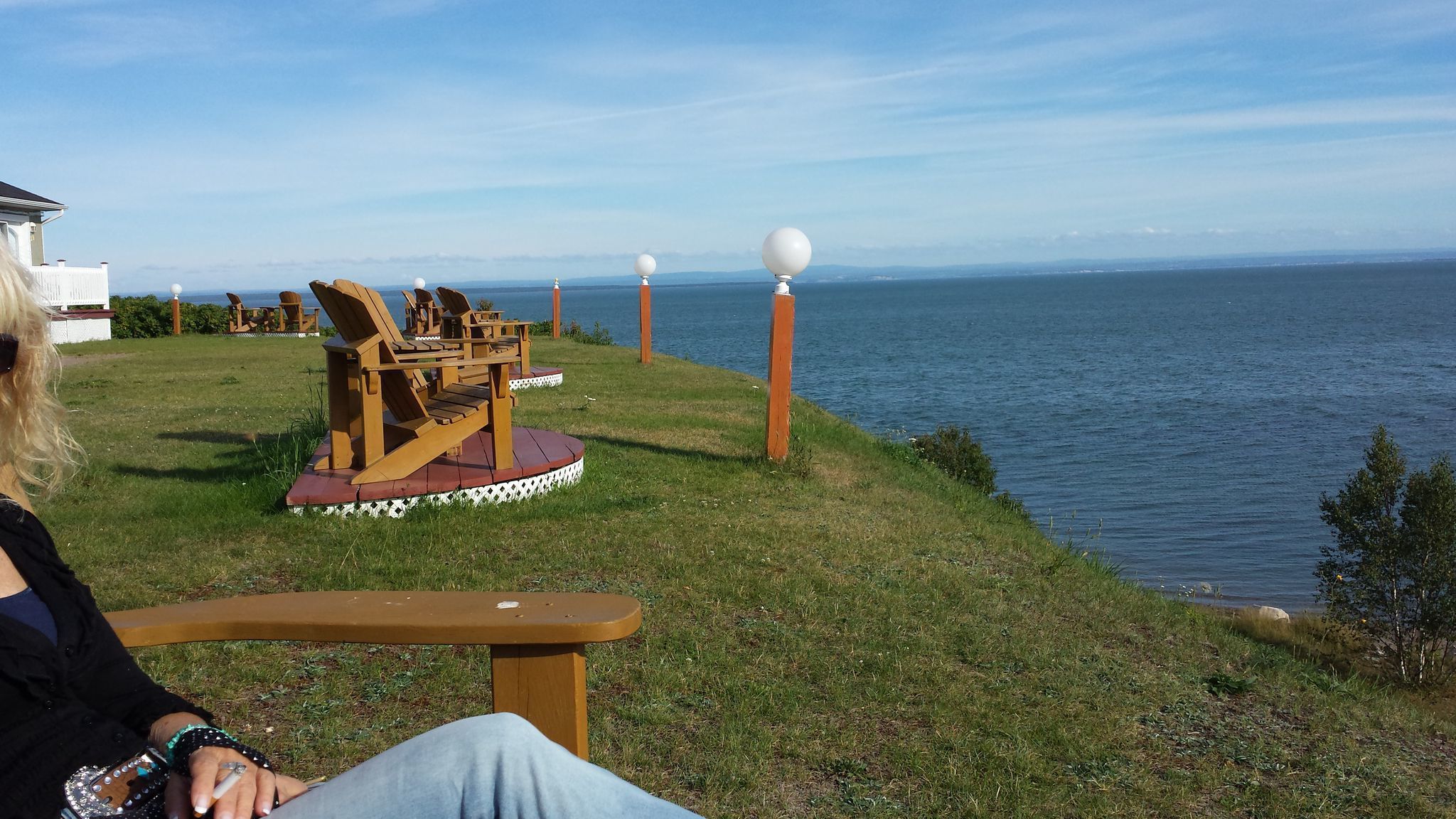 Terraza de madera con una silla y una mesa con vistas al agua.