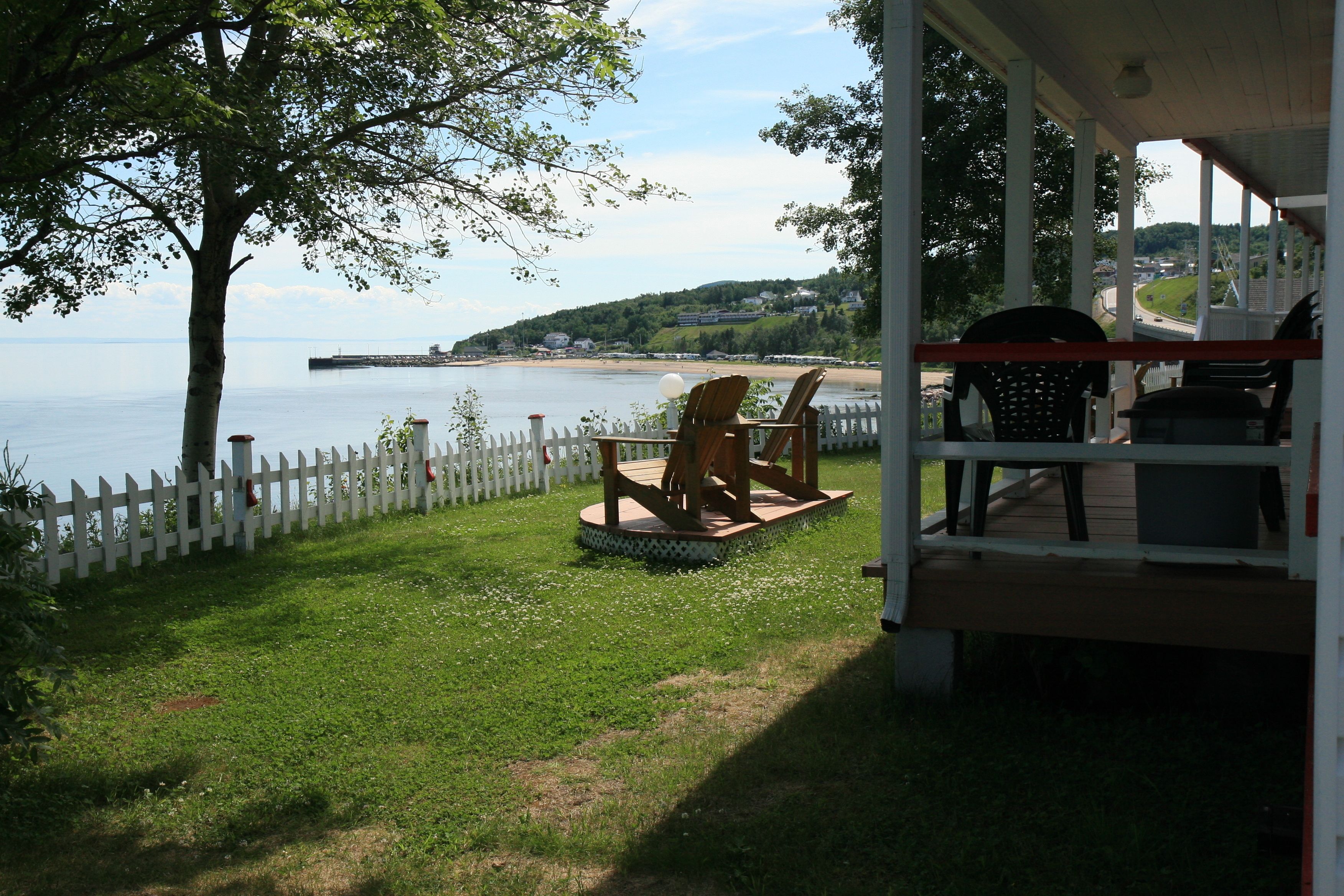 A deck with outdoor seating overlooking a body of water and a distant shoreline.