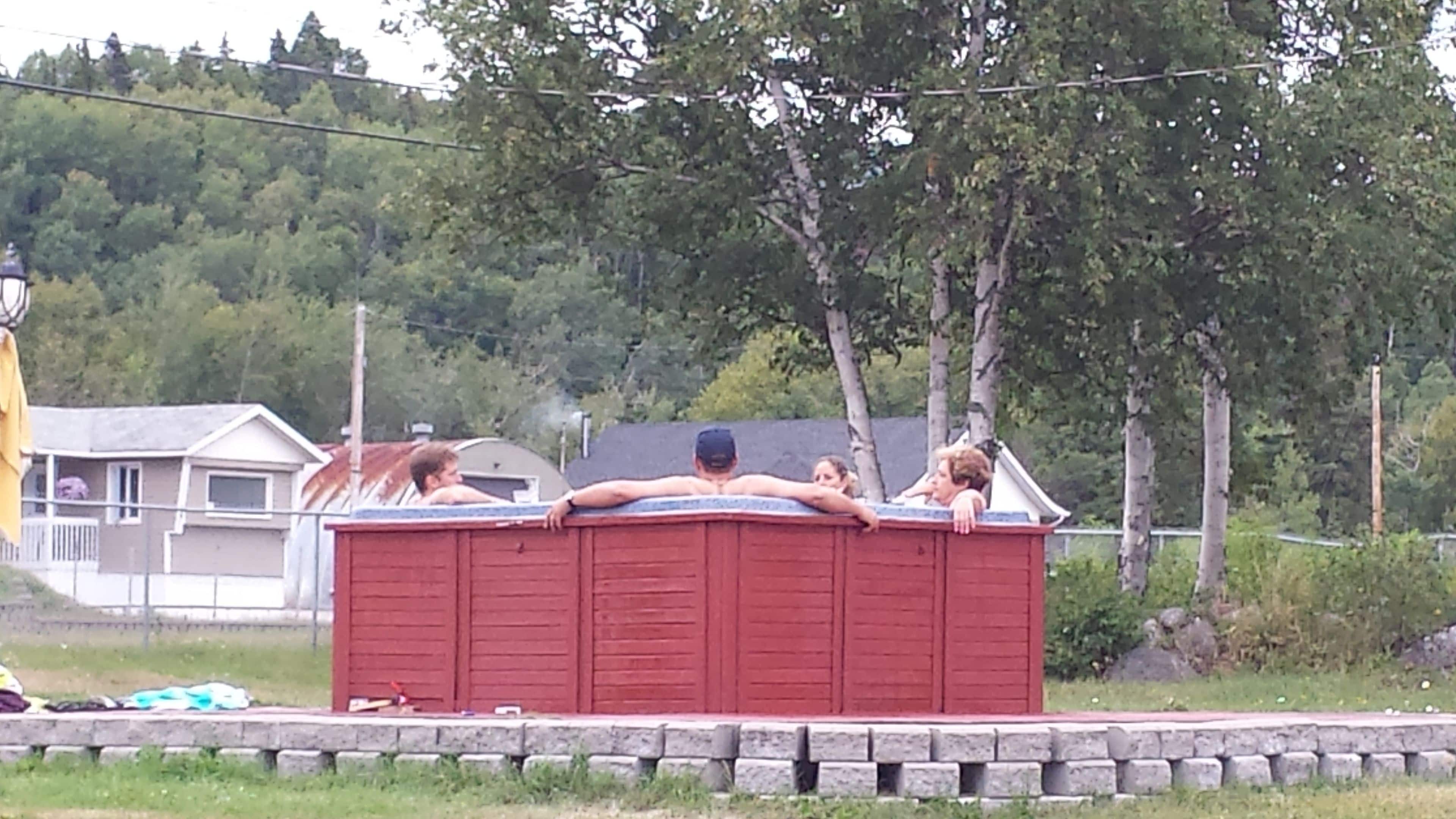 A red hot tub with three people relaxing in it.