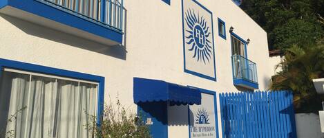 Un edificio con fachada azul y blanca, un símbolo de sol y el nombre 'The Hyperion Boutique Hotel & Bar'.