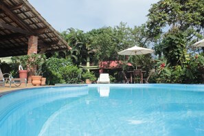 A swimming pool with a tiled edge, surrounded by potted plants and a covered seating area. - Pousada Atlântica (Itacaré)