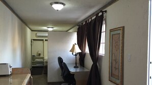 Habitación con escritorio, silla, lámpara y cortinas.