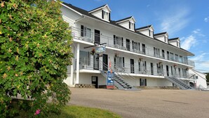 A two-story building with a balcony, a staircase, and a signboard. - Auberge Sur Mer de Charlevoix (Saint-Simeon)
