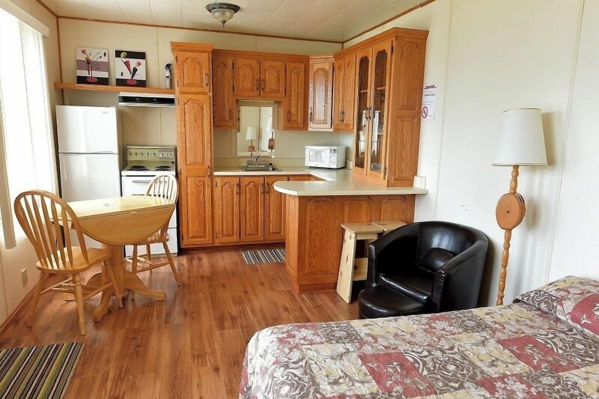 A compact kitchen with wooden cabinets, a dining table, and a black chair.