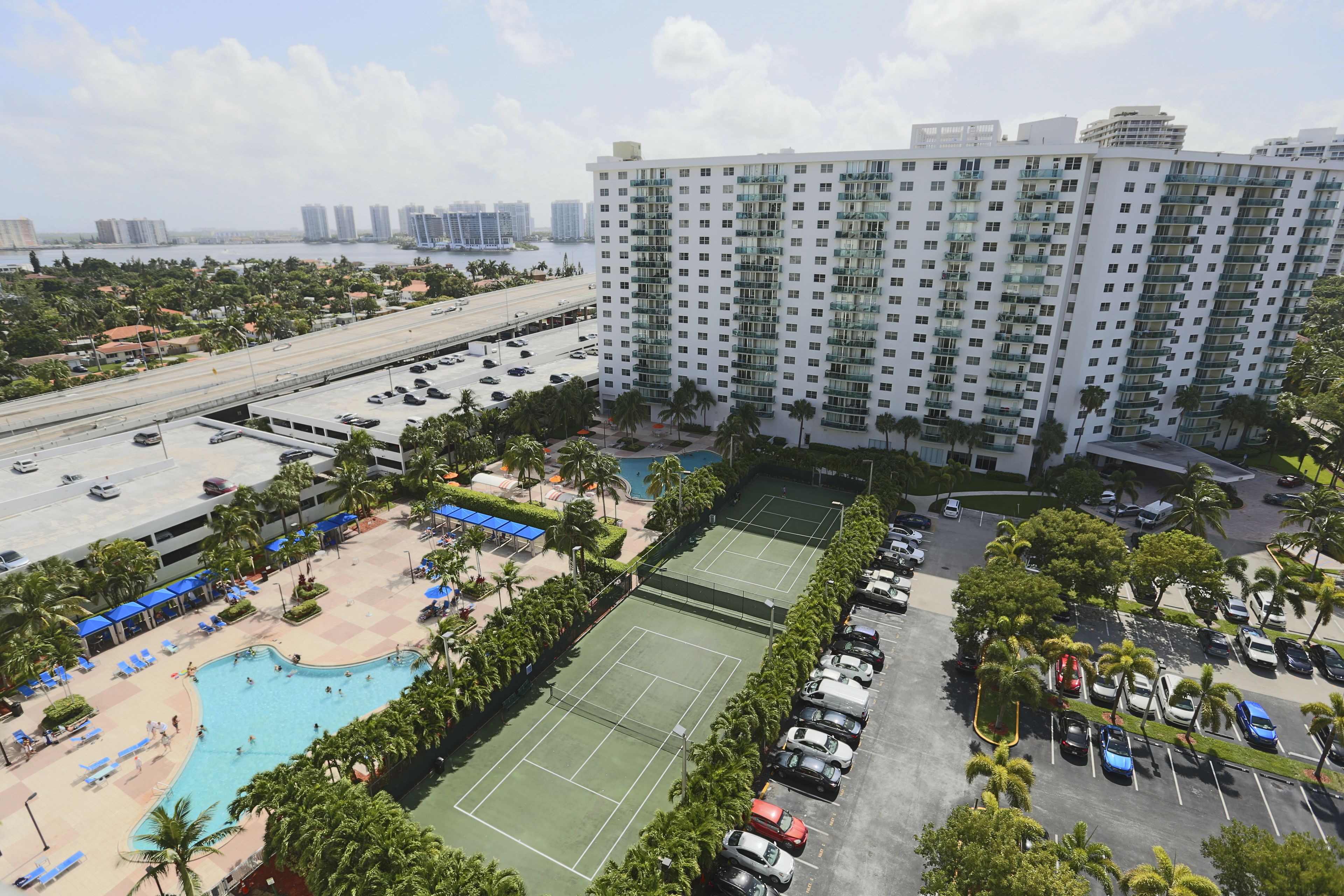 Un hotel moderno con piscina, canchas de tenis y estacionamiento.