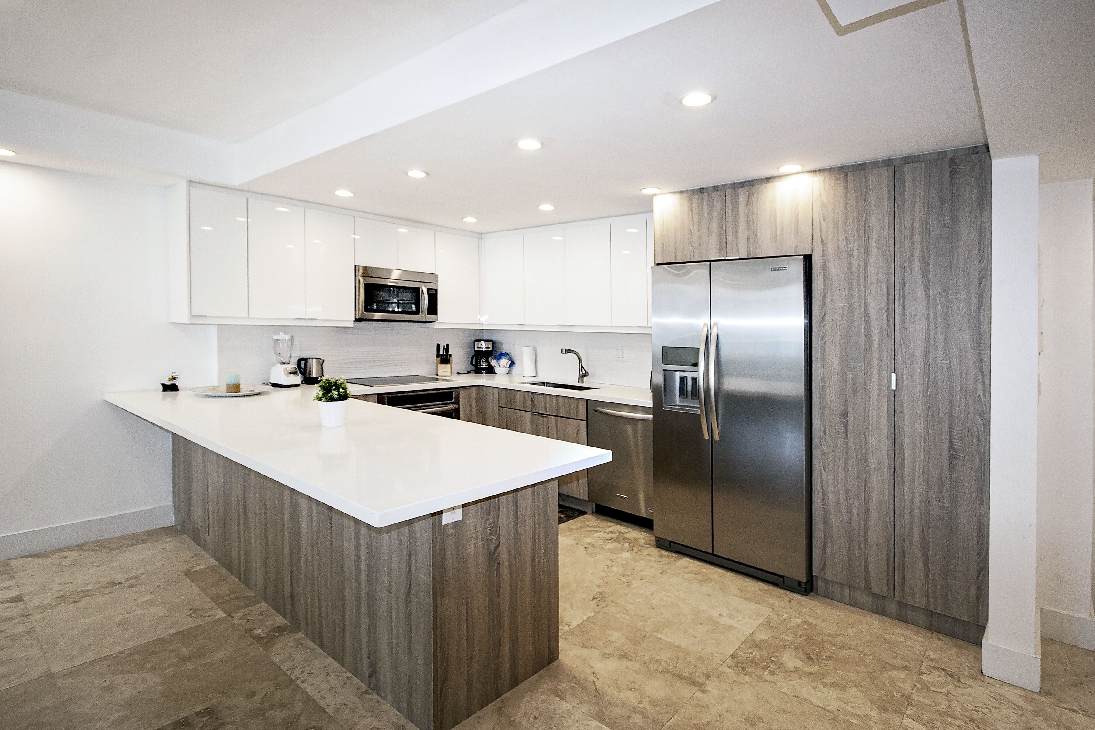 A modern kitchen with white cabinetry, a central island, stainless steel appliances, and a wooden accent wall.