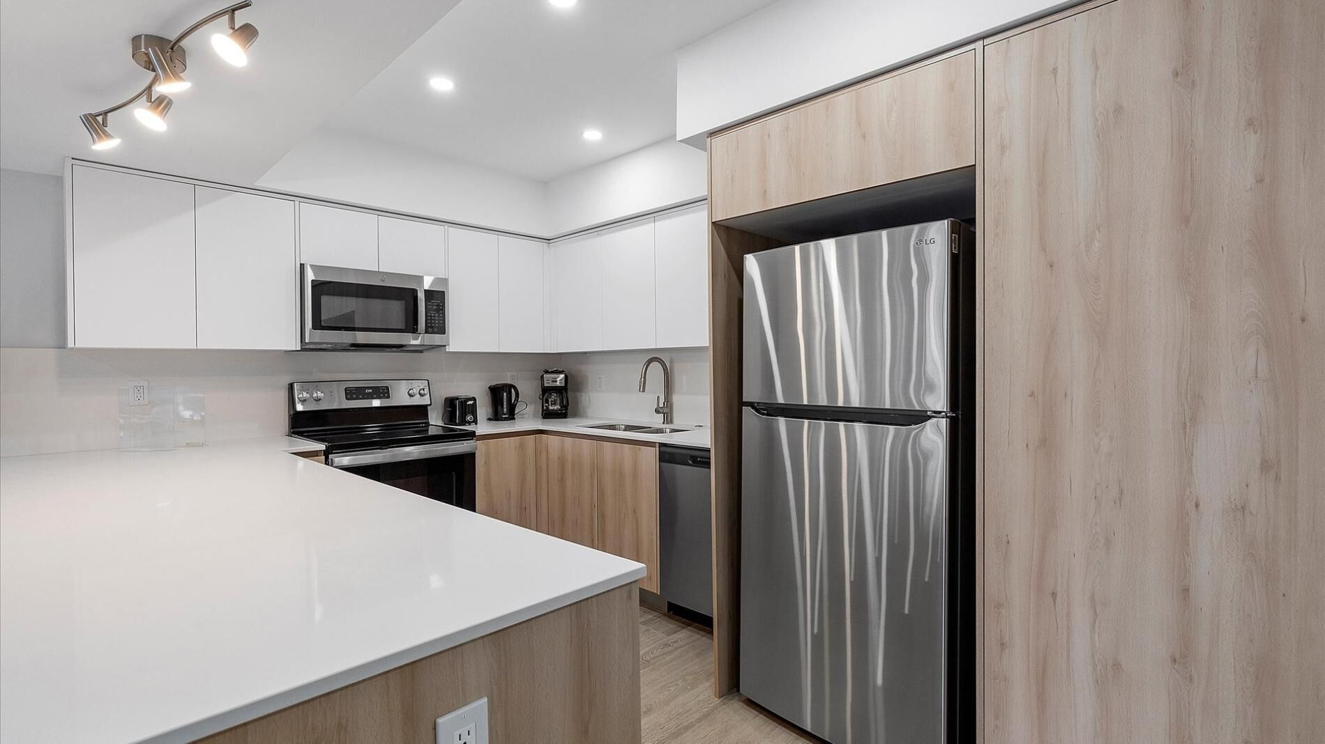 A modern kitchen with white cabinetry, stainless steel appliances, and a large island.