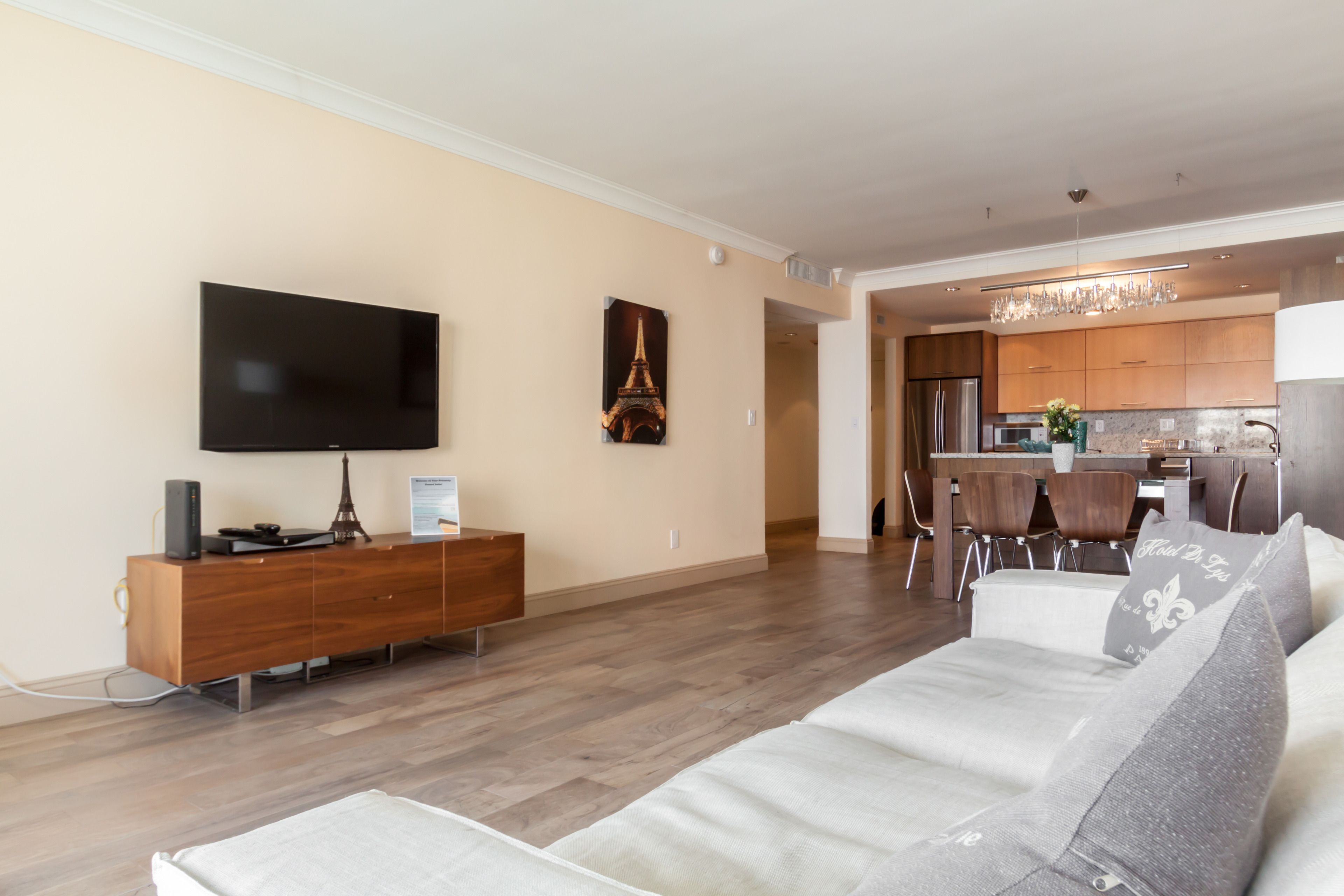 A modern living room with a flat-screen TV, a wooden entertainment unit, and a sofa.