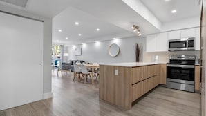 A modern kitchen with built-in appliances, a dining area with a wooden table and chairs, and a large island with a wooden countertop. - Ocean Reserve Luxury Condos Across from Sunny Isles Beach (Sunny Isles Beach)