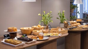 A buffet setup with various food items and a sign indicating 'Bolo de Amendoim'. - Tropikalya Gold Hotel (Balneário Camboriú)