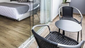 A modern bedroom with a bed, a glass partition, a potted plant, and a small table with chairs. - Tropikalya Gold Hotel (Balneário Camboriú)