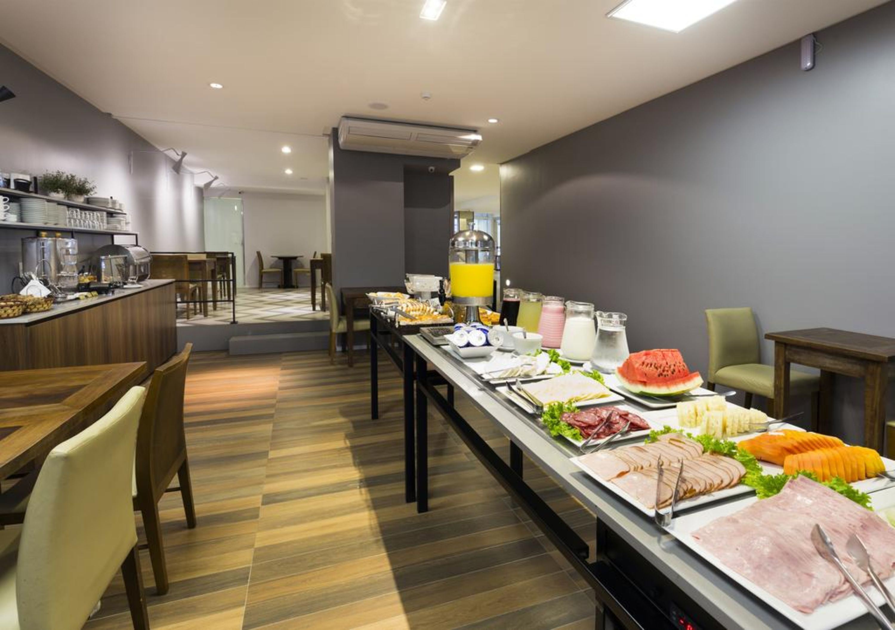 A buffet setup with various food items and a juice dispenser.