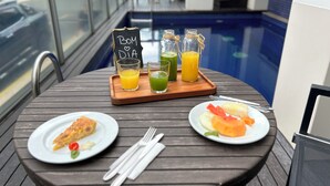 A table with breakfast items including a slice of pizza, a plate of fruit, and a tray with drinks. - Tropikalya Gold Hotel (Balneário Camboriú)