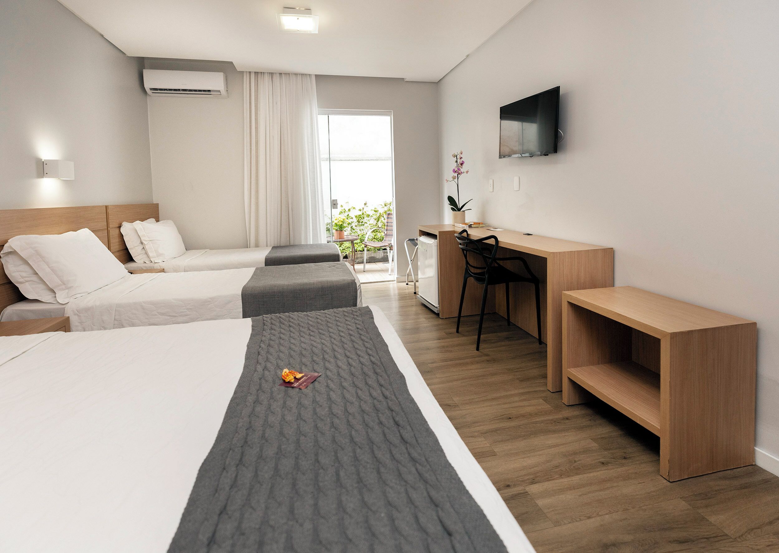 Une chambre d’hôtel avec deux lits, un bureau, une télévision et une vue sur l’extérieur.
