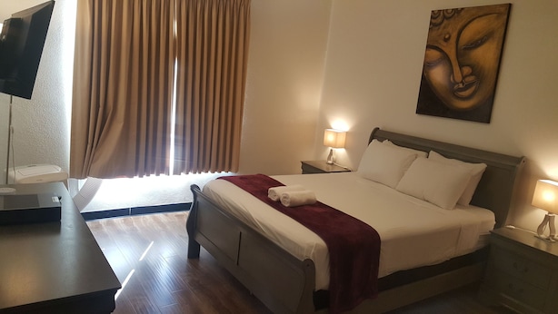 Een hotelkamer met een bed, een bureau, een televisie en een schilderij aan de muur.