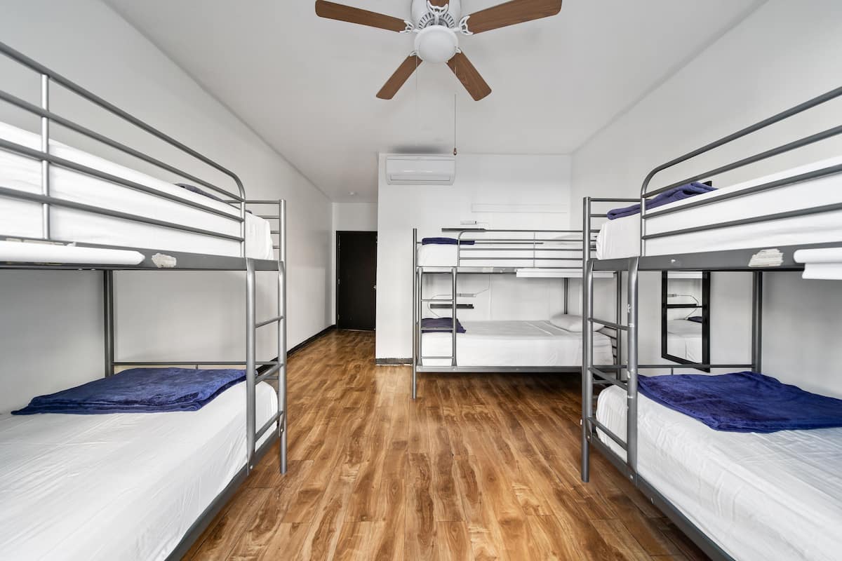 Een slaapzaal met stapelbedden, een plafondventilator en een airconditioning.